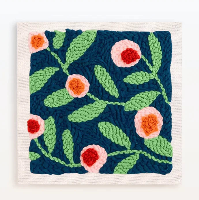 Punch needle embroidery kit featuring a dark blue background with pink and orange floral patterns.