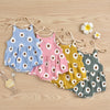 A set of three baby girl floral print cotton rompers in blue, pink, and yellow laid out on a wooden surface.