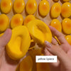 A hand holds a yellow squishy cheese cake stress relief toy with other similar toys in the background.