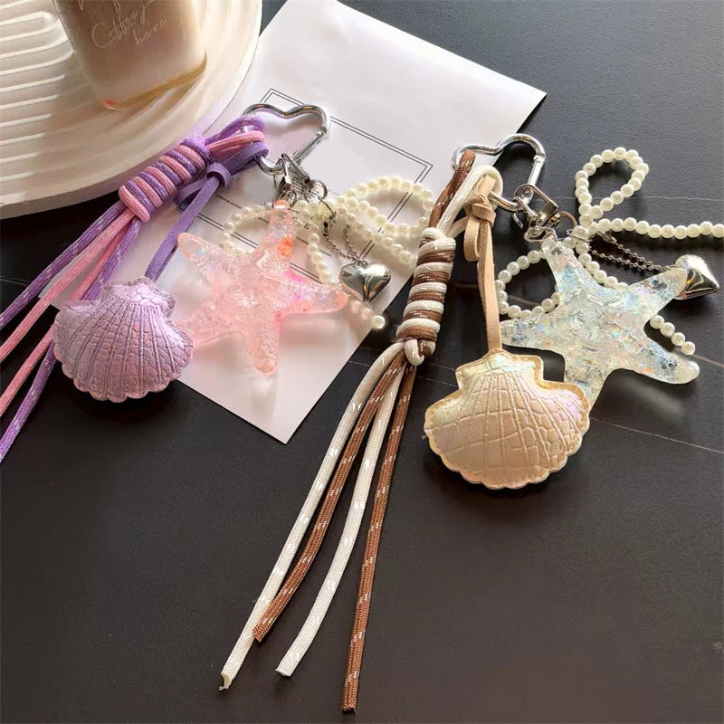 A collection of beaded keychains featuring starfish, shells, and pearls on a white card.