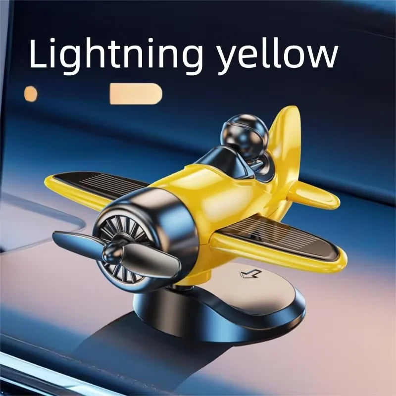 A lightning yellow solar powered rotating airplane dashboard ornament resting on a dark surface.