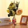A bouquet of dried flowers and green foliage with a glass vase filled with sparkling red and orange acrylic gemstones.