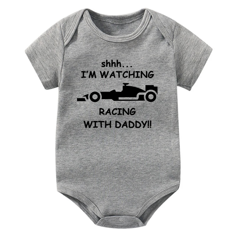 A gray baby bodysuit featuring text that reads Shhh I'm watching Racing with daddy