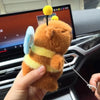 An orange capybara plush toy with yellow stripes and blue wings is being held by a hand.