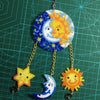 A hanging craft project made from colorful fuse beads shaped like a sun and moon on a green grid background.