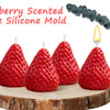 A silicone mold shaped like a strawberry is shown with a lit candle, resting on a wooden slice.