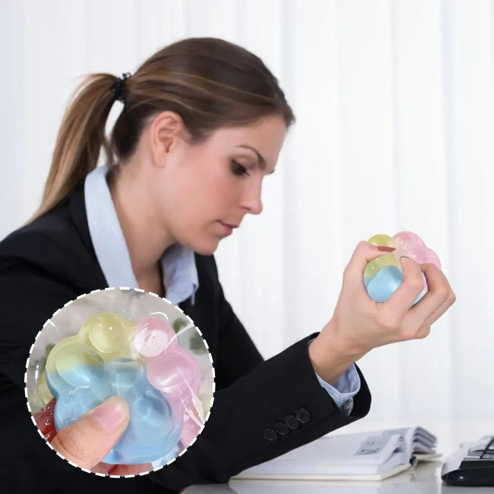 A woman holds a translucent blue and pink squishy toy in her hand against a white background.