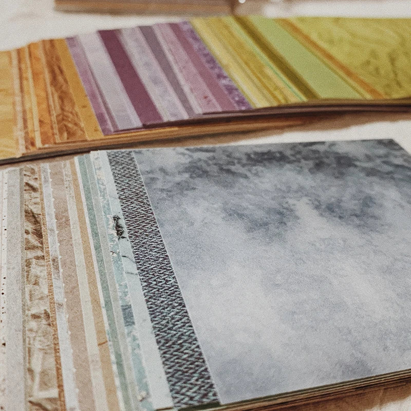 A close-up of a pack of rainbow textured paper sheets with various colors and patterns for junk journaling.