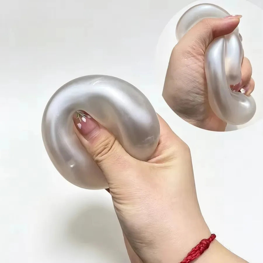 A hand holds a clear, slow-rising squishy stress ball with a coconut scent, demonstrating its shape and texture.