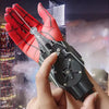 A hand holds a red and black electric auto-retractable wrist-mounted web shooter for cosplay against a city backdrop.