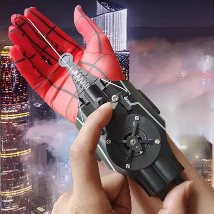 A hand holds a red and black electric auto-retractable wrist-mounted web shooter for cosplay against a city backdrop.
