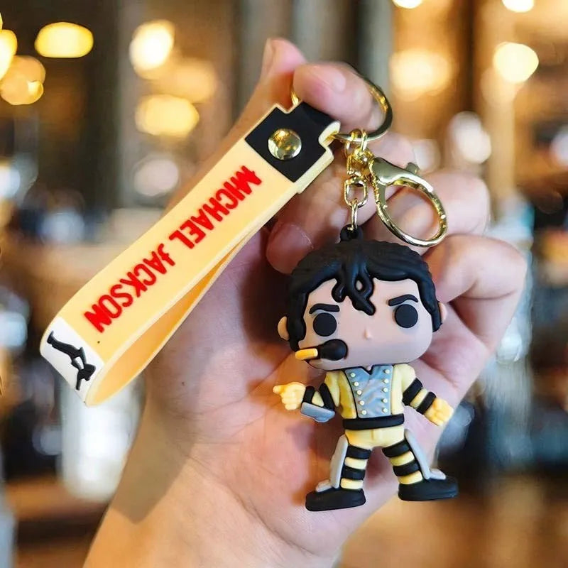 A hand holds a Michael Jackson music icon keychain featuring a figure of Jackson in a suit.