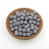 A pile of small gray silicone round beads in a wooden bowl for jewelry making and crafts.