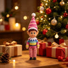 A small elf decoration wearing a pink and white hat stands in front of a decorated Christmas tree.