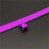 A purple glitter origami star paper strip is shown lying on a dark surface.