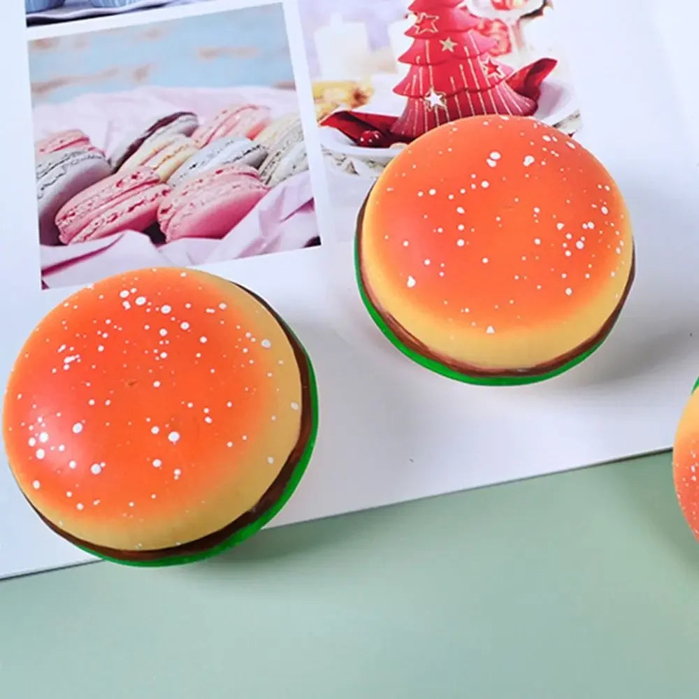 An orange and yellow squishy stress ball shaped like a burger with white sprinkles.