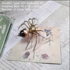 A finished steampunk metal spider DIY assembly kit with gold and bronze parts displayed on parchment paper.