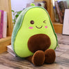 A cute, light green avocado plush toy with brown accents sitting on a wooden surface.