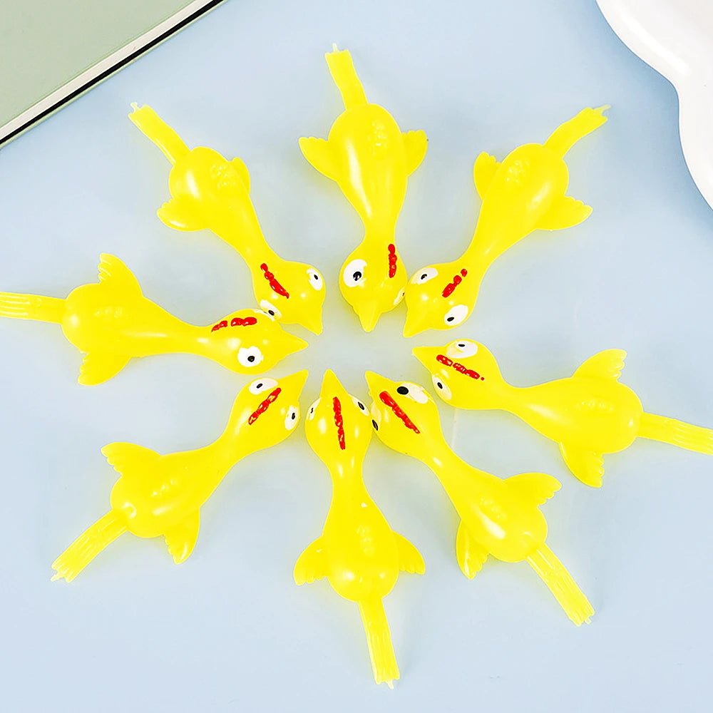 Several bright yellow catapult chicken flying toys are arranged on a light blue surface.