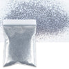 A white bag of holographic fine glitter powder scattered across a white surface.