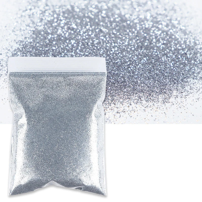 A white bag of holographic fine glitter powder scattered across a white surface.