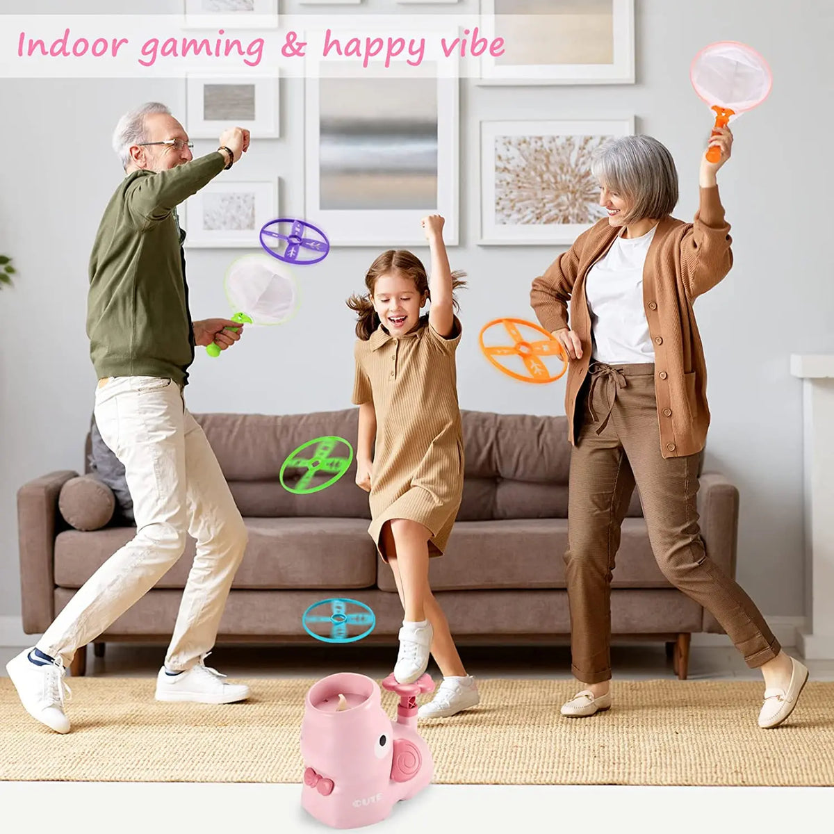 A woman and a man are playing with a pink foot launcher flying disc toy set indoors.