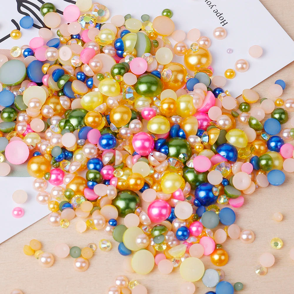 A close-up of mixed resin rhinestone pearls in various colors including pink, yellow, blue, and green scattered on a white ba