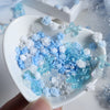 A white dish filled with blue and white camellia bowknot resin shakers for DIY crafts