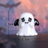 A white ceramic figurine shaped like a cartoon pumpkin bear with black eyes and ears.