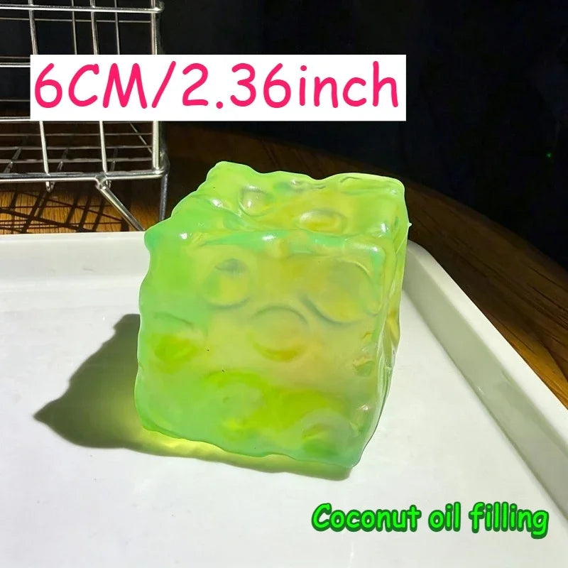 A translucent lime green squishy stress ball filled with coconut oil, shown on a white surface.