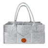 A light gray felt diaper storage bag with long handles and a flap closure.