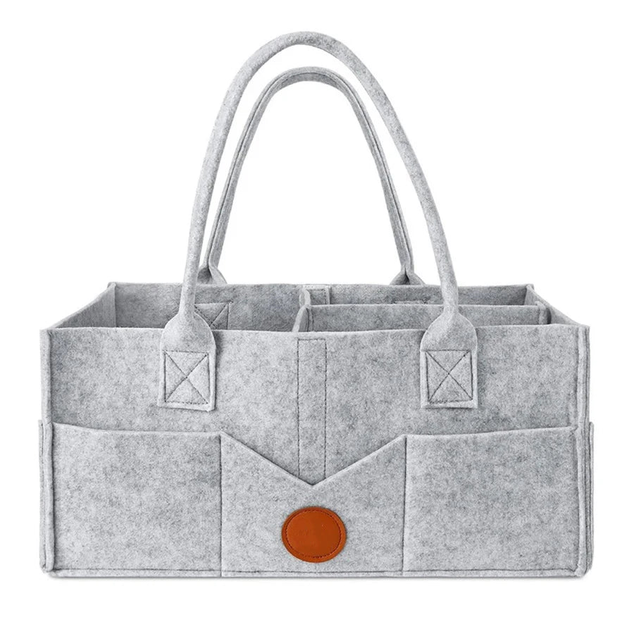 A light gray felt diaper storage bag with long handles and a flap closure.