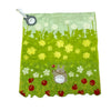 A bright green fabric towel featuring a pattern of white flowers and small yellow plants, with a small gray hippo plush toy a