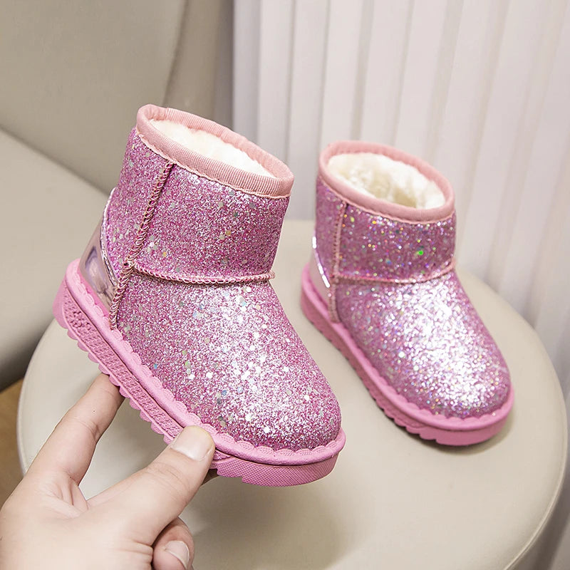 A pair of sparkly pink winter snow boots with faux fur lining resting on a light surface.