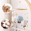 Natural wood and cotton rattles hanging from a string mobile for an infant crib