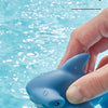 Una mano está apretando un juguete de agua en forma de delfín azul dentro del agua.