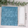 A square blue textured clay roll with floral patterns next to a white rolled paper.