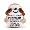 A handmade crochet owl with brown and white feathers smiling and holding a sign that reads Positive Sloth