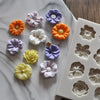 A collection of purple, orange, and white silicone flower molds for chocolate and cake decorating
