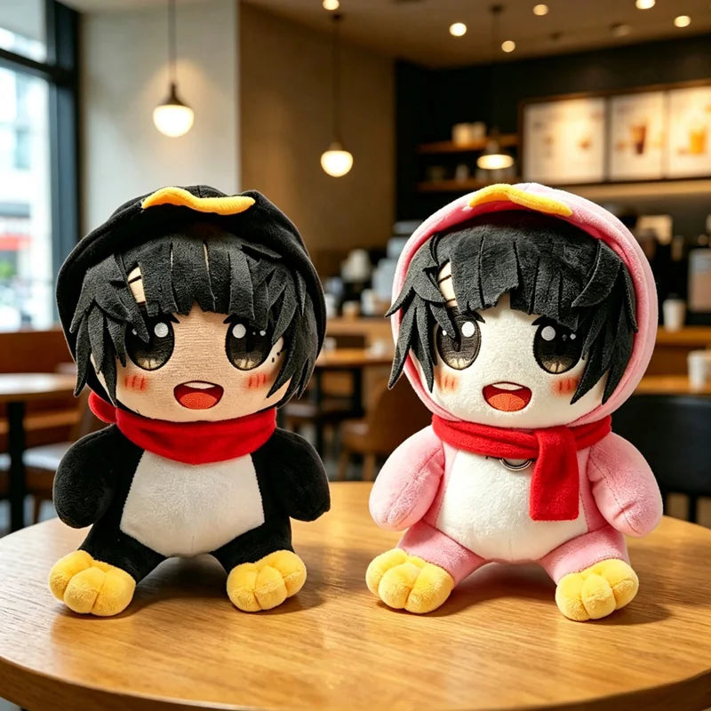 A pair of black and white penguin plush toys with red scarves sitting on a wooden table.