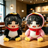 A pair of black and white penguin plush toys with red scarves sitting on a wooden table.