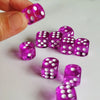 A hand holds a set of vibrant purple and pink transparent dice on a white surface.