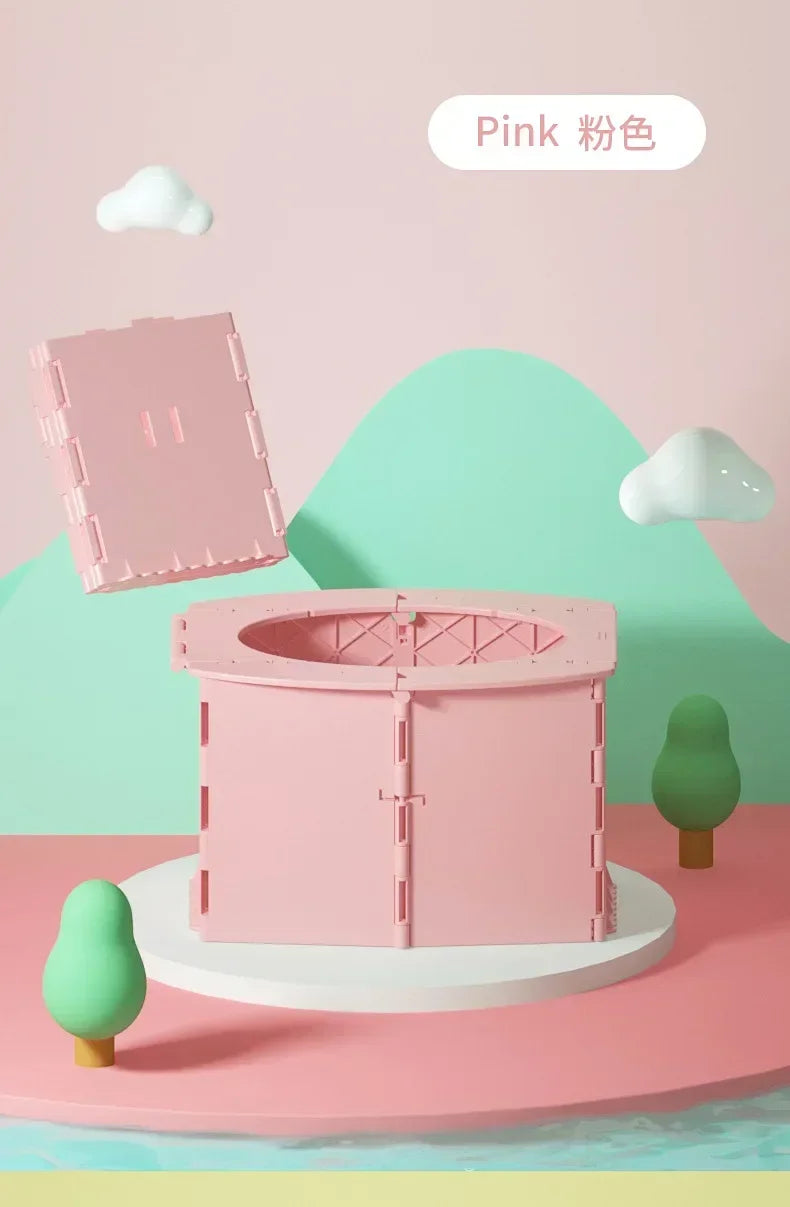 A pink foldable baby potty training seat is displayed on a white stand against a light green background.