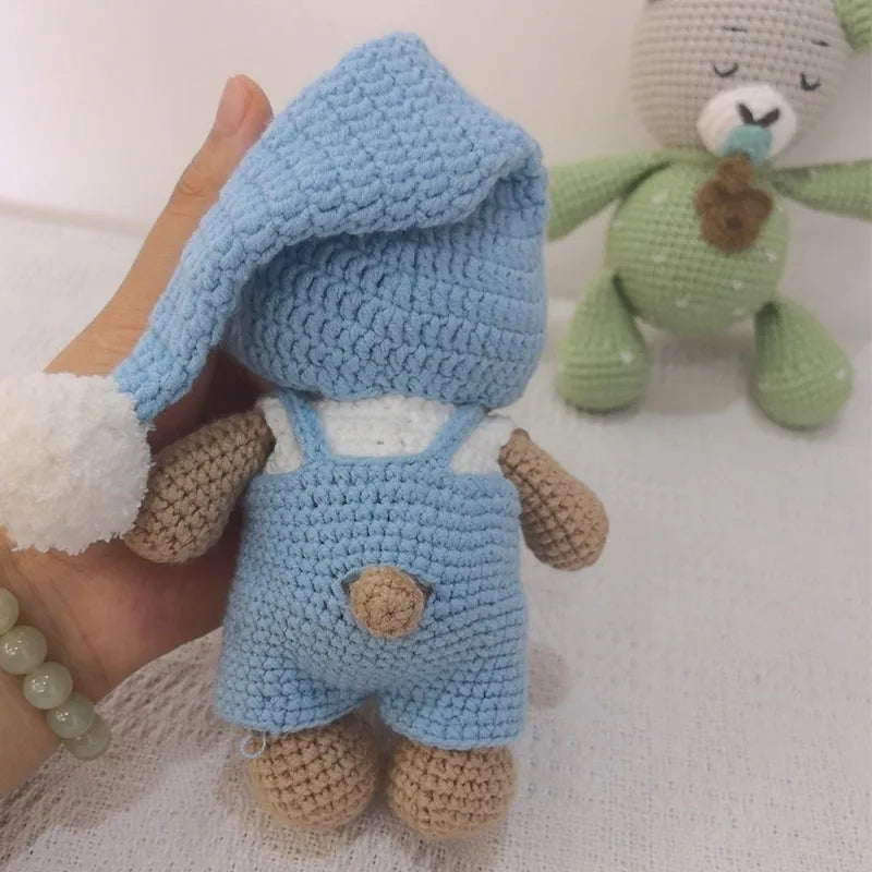Handmade crochet stuffed bear in light blue with white accents and a green plush toy in the background