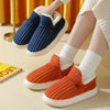 A pair of women's cozy faux fur slippers in navy blue and orange are shown on a light surface.
