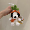 A white Snoopy plush charm with green leaves and an orange hat is being held against a light background.
