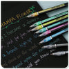 A collection of metallic glitter gel pens in various colors resting on a black surface.