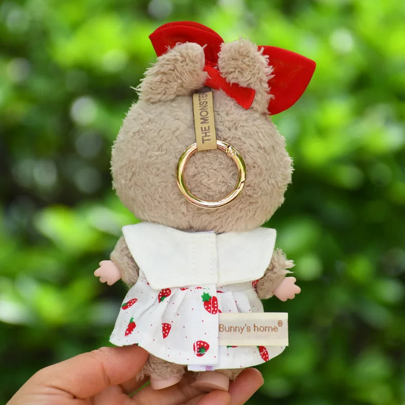 A plush bunny doll wearing a white dress and red bow, held in a person's hand.