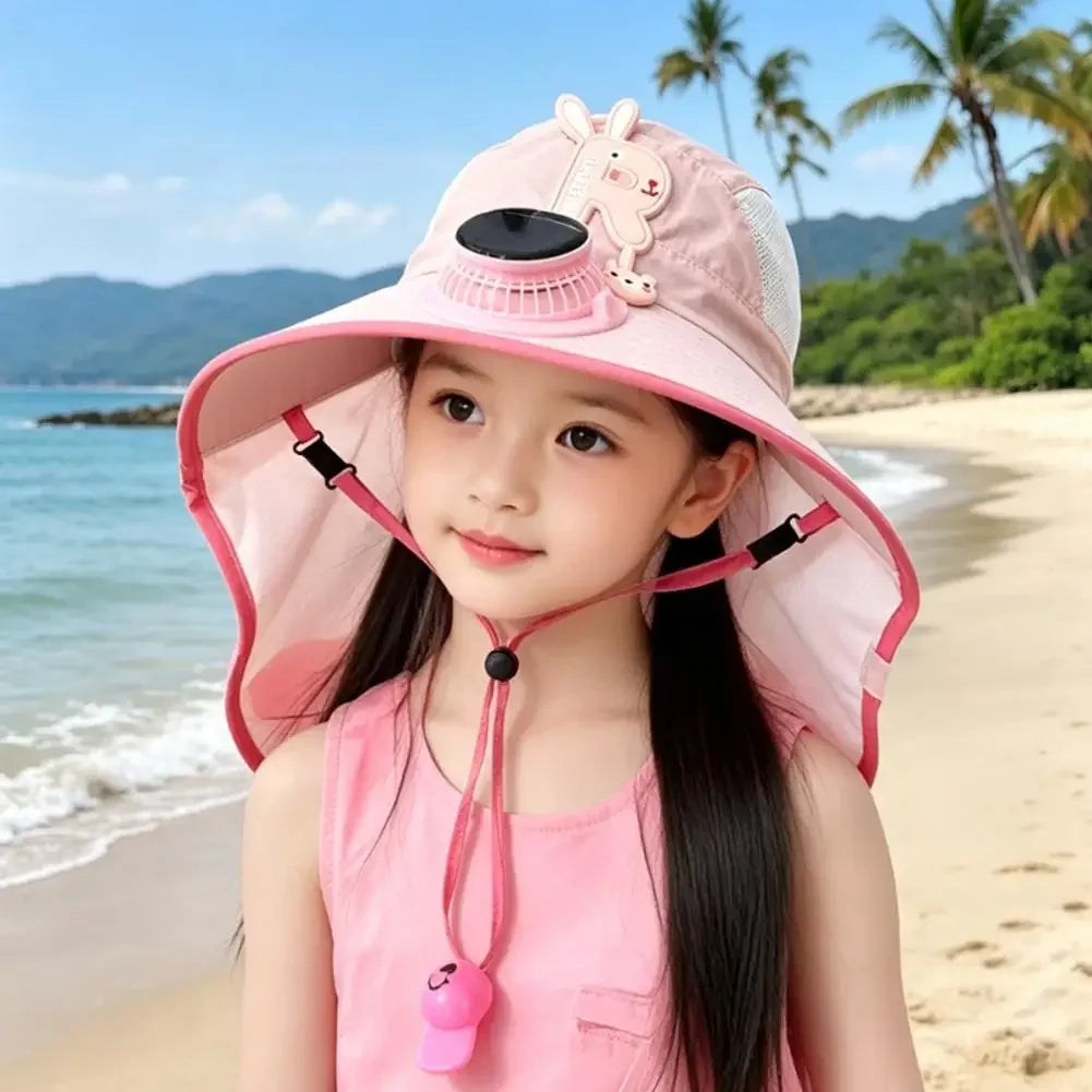 A young girl wearing a pink sun hat with a rabbit design and a pink top, standing on a beach.