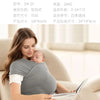 A woman is wearing an ergonomic baby sling carrier while sitting on a sofa, holding a baby.